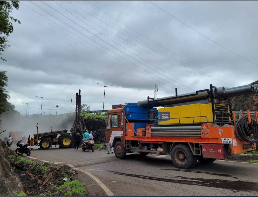 Truck-mounted borewell drilling rig at a roadside site